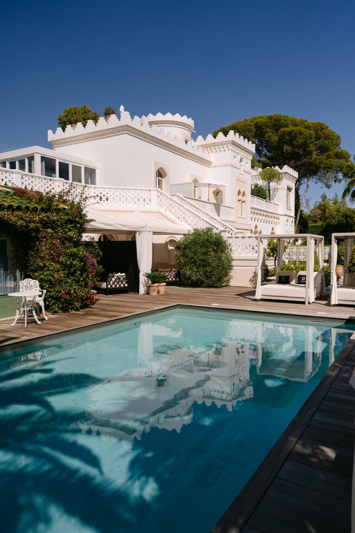 La piscine et la façade d'un château blanc, sous un ciel bleu profond