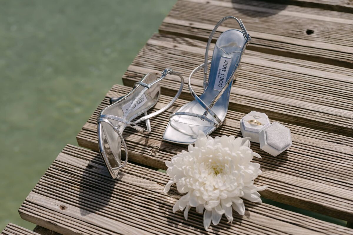 Les chaussures argentées de la mariée et une fleur blanche sur un ponton en bois