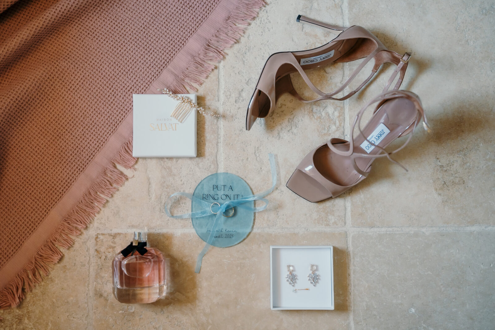 Photographe mariage Sainte-Maxime 5 Escarpins roses, parfum et boucles d'oreilles disposés sur une pierre claire