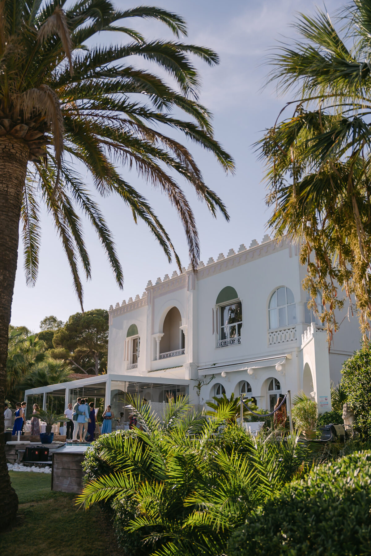Une villa blanche entre les palmiers, les invités sur la terrasse