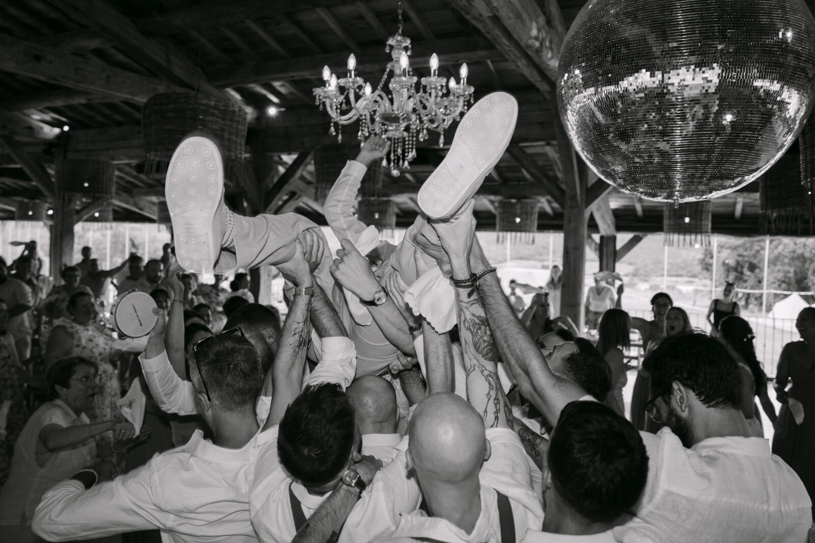 Accueil 22 En noir et blanc, un invité porté par la foule sous un lustre et une boule à facettes
