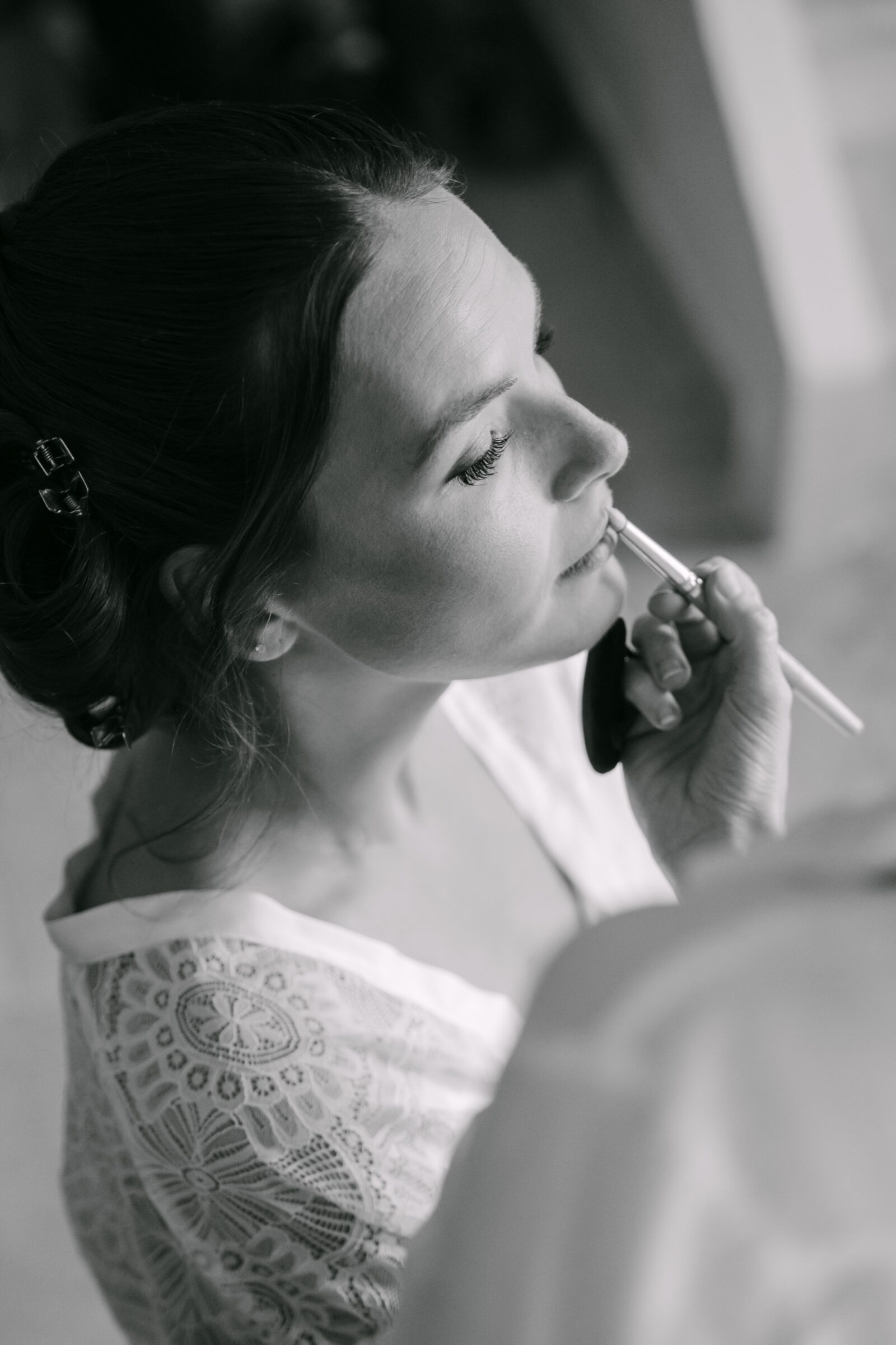 Mon approche 2 En noir et blanc, la mariée de profil pendant qu'on termine son maquillage