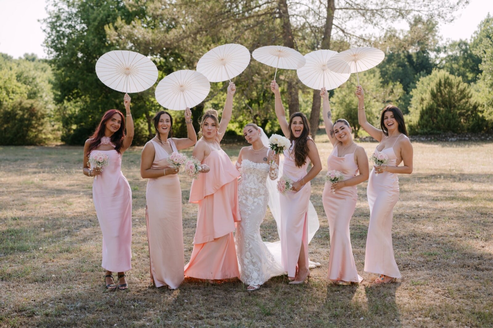 Accueil 8 La mariée et ses demoiselles d'honneur en robes rose poudré lèvent leurs ombrelles blanches en riant