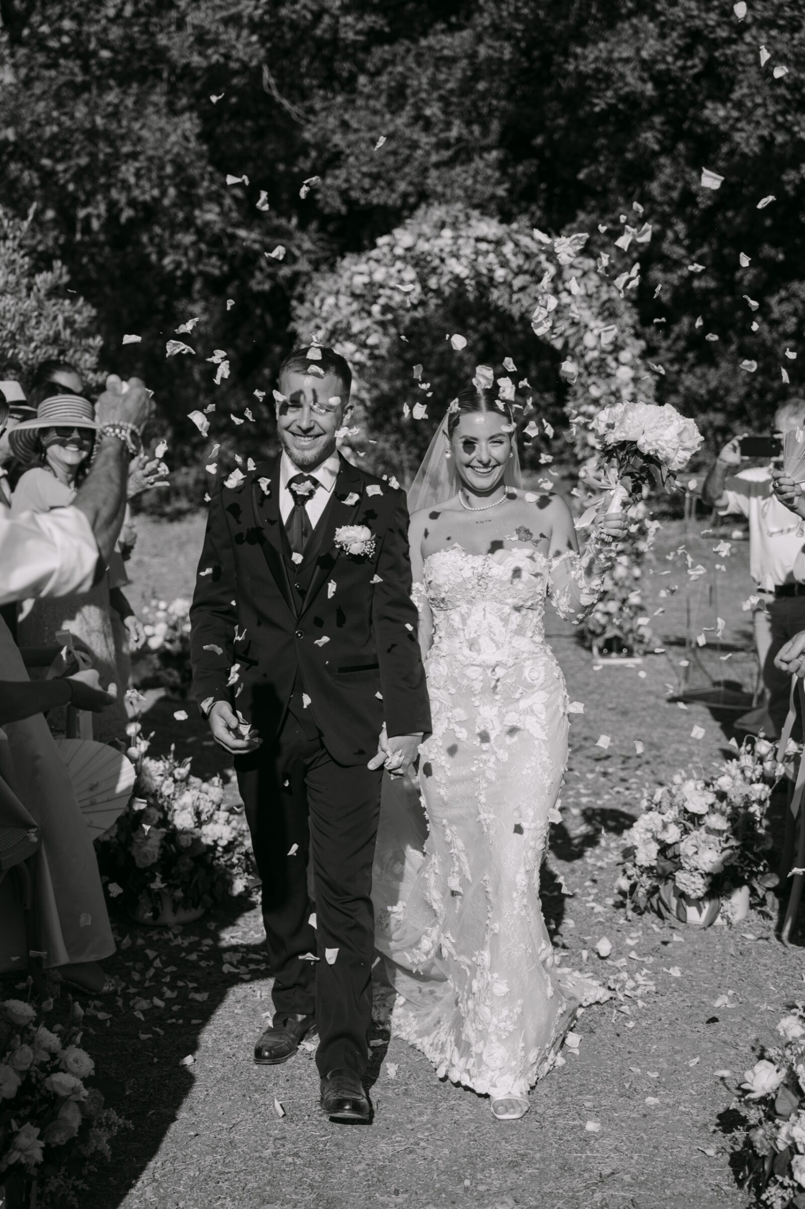 Photographe mariage Flayosc 4 En noir et blanc, les mariés avancent sous une pluie de pétales lancés par leurs proches