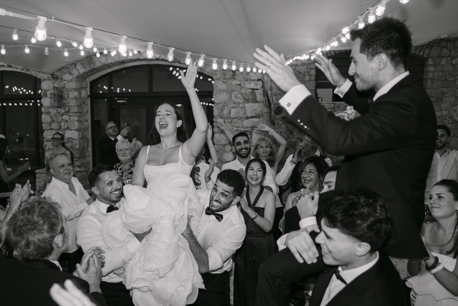 Les photos de vos invités de mariage : la moitié de l’histoire 8 En noir et blanc, la mariée rit aux éclats au milieu des invités qui dansent sous les guirlandes