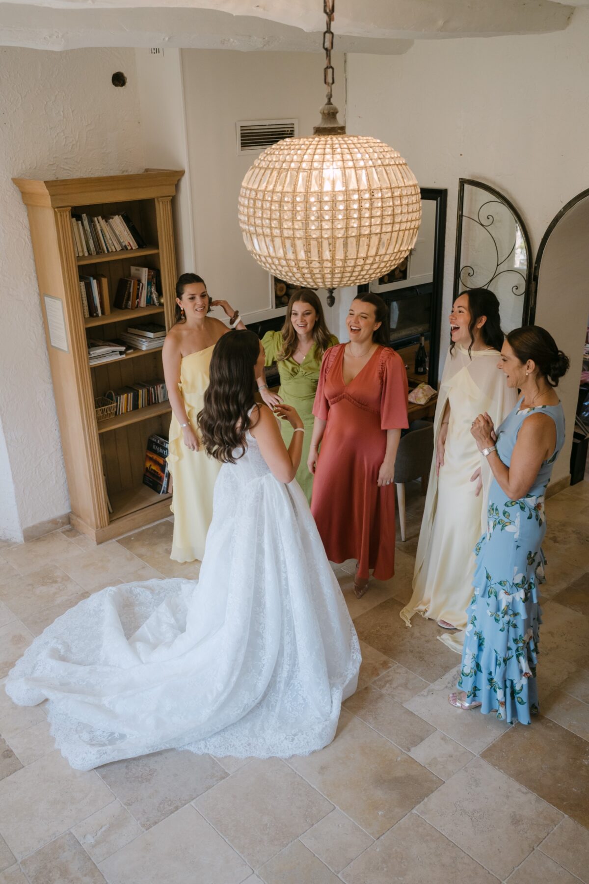 La mariée entourée de ses amies en robes colorées dans une pièce lumineuse, avant la cérémonie