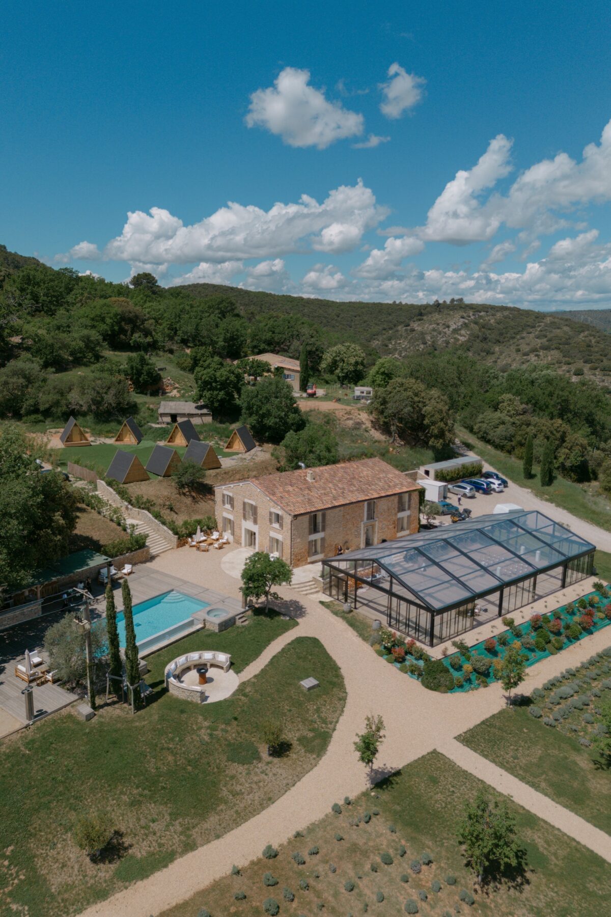 Vue aérienne d'un domaine provençal, sa piscine et sa verrière au milieu des collines