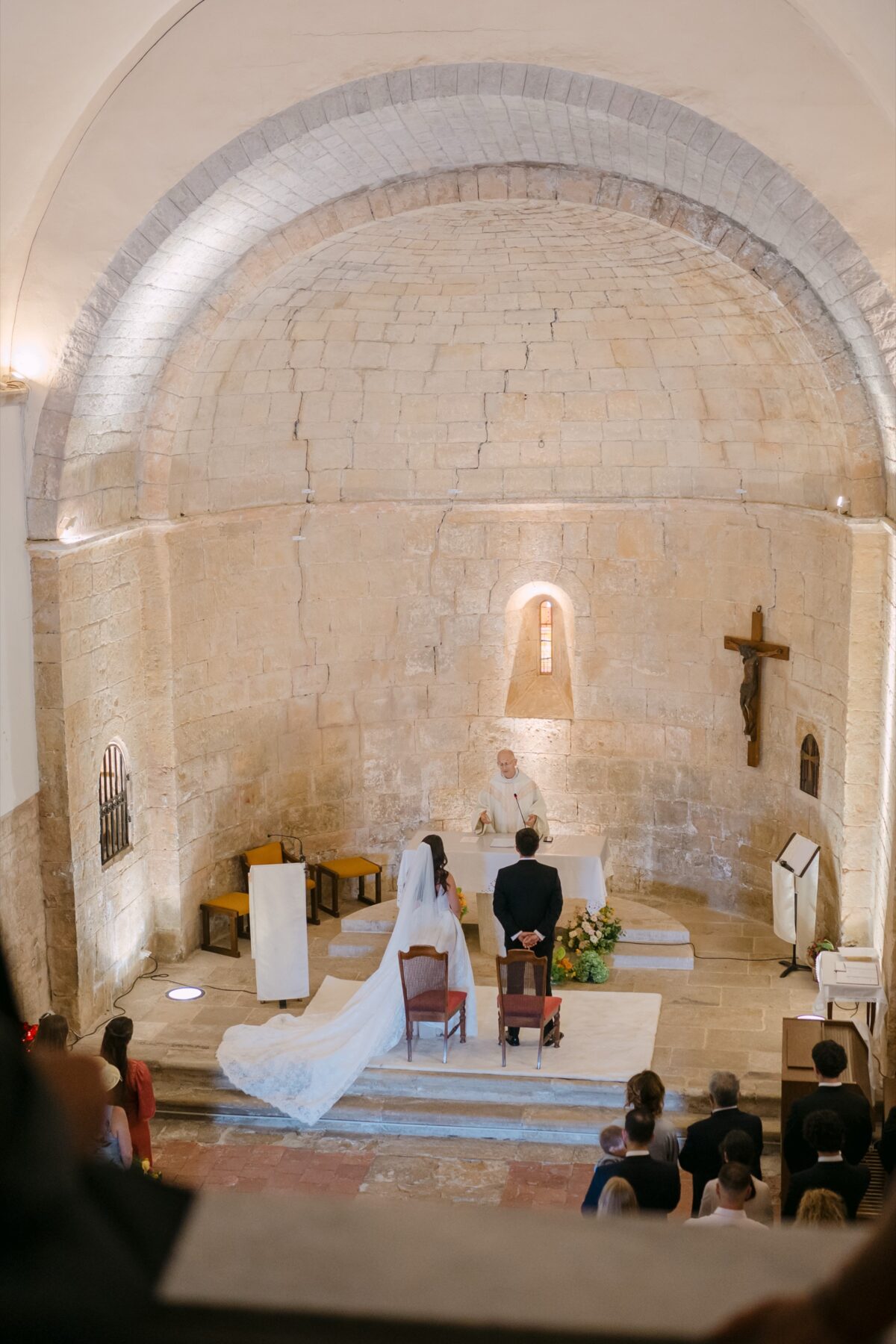 Cérémonie dans une petite chapelle romane, vue depuis le fond, les mariés devant l'autel